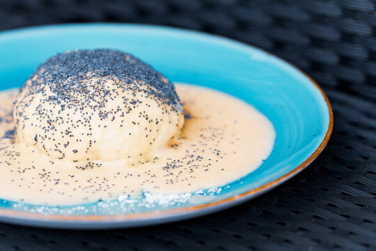 Steamed sweet dumpling bun topped with poppy seeds and vanilla sauce.