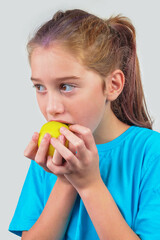 Girl in a blue shirt eating yellow apple