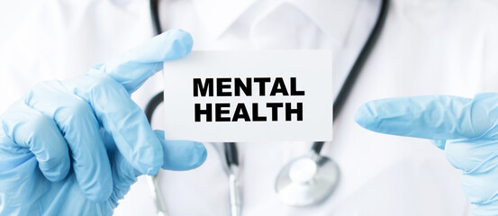 Doctor holding a card with text Mental Health, medical concept, close-up.
