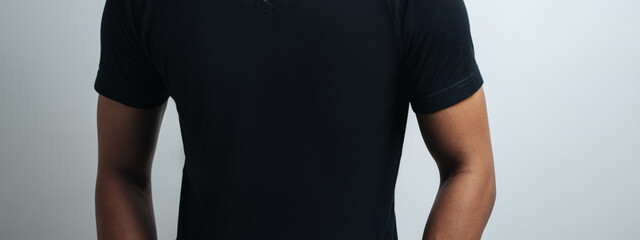 man in black blank t-shirt, empty wall, studio close-up, casual style. Wide screen, panoramic