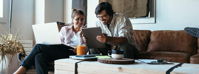 Group of two people with laptops in small loft office. Man and woman working together. Pleased with...