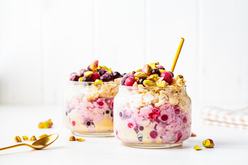 Overnight oats with berries and nuts in jars on a white background. Healthy breakfast concept.