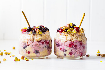 Overnight oats with berries and nuts in a jar on a white background, copy space. Healthy breakfast...