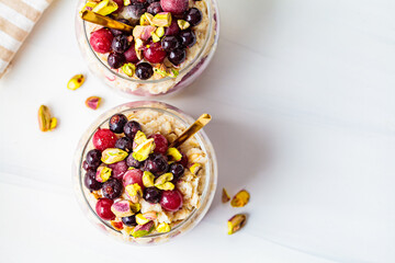 Overnight oats with berries and nuts in jars on a white background, top view. Healthy breakfast concept.