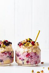 Overnight oats with berries and nuts in jars on a white background. Healthy breakfast concept.