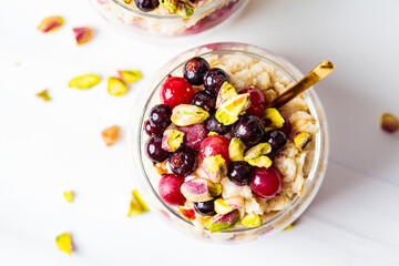 Overnight oats with berries and nuts in jars on a white background, top view. Healthy breakfast concept.