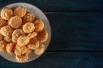Amaretti, traditional Italian almond cookies, shot from above with a place for text on a dark blue wooden background