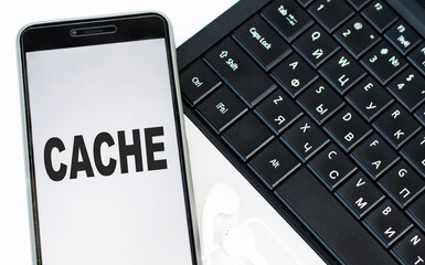 Cache word is written on the phone, which is on the laptop keyboard. © Volha