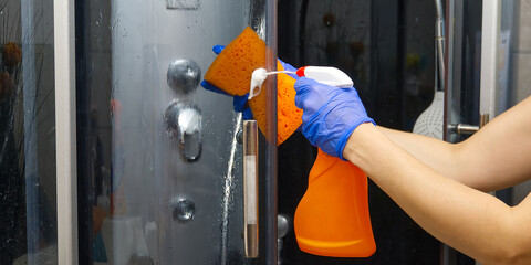 Cleaning of shower steam cabins from calcium deposits. Cleaning in the bathroom. hand in gloves with rag and detergent washing shower and glass