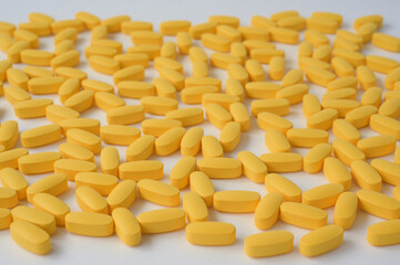 pharmacy concept of handful of yellow pills tablets lying on white surface