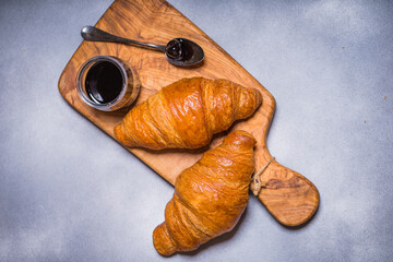 French croissant. Freshly baked croissants with jam on wooden background. Tasty croissants with copy space