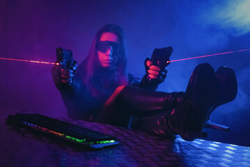 A girl with a toy guns is sitting in the smoke by the table with a computer keyboard above.