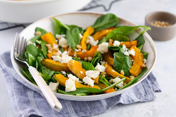 Salad of spinach leaves, baked pumpkin and feta cheese with nuts. Healthy food.
