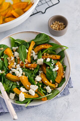 Salad of spinach leaves, baked pumpkin and feta cheese with nuts. Healthy food.