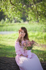 beautiful girl in a pink dress walks with a bouquet of pink flowers, a photo session in a fairy-tale style at sunset