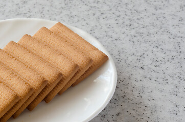 Rectangular shortbread cookies and chocolates in a white plate on a marble top.