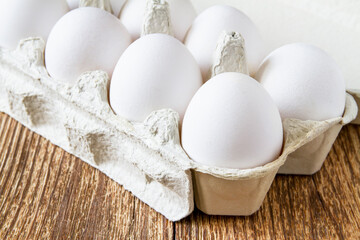 Close-up of fresh white organic chicken eggs in the paper tray on wooden background
