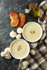 Concept of tasty lunch with bowls of mushroom soup on black smoky background