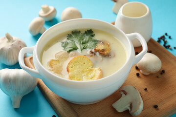 Concept of tasty lunch with bowl of mushroom soup on blue background
