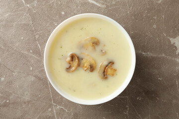 Bowl of tasty mushroom soup on gray background