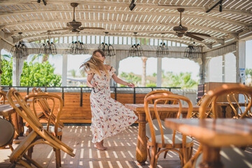 girl dancing in cafe on the beach. young slim beautiful woman on sunset beach, playful, dancing, running, bohemian outfit, indie style, summer vacation, sunny, having fun, positive mood, romantic