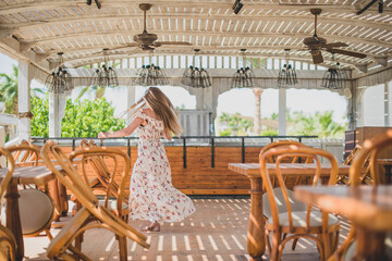 girl dancing in cafe on the beach. young slim beautiful woman on sunset beach, playful, dancing, running, bohemian outfit, indie style, summer vacation, sunny, having fun, positive mood, romantic