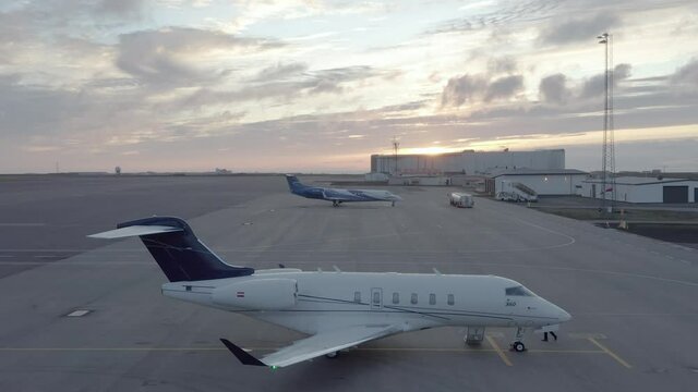 Aerial of sunrise with Bombardier jet parked on tarmac with pilot doing checks