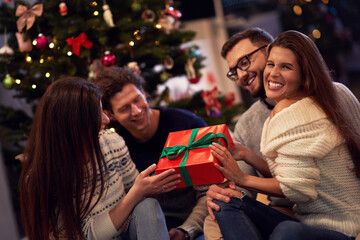 Group of friends with presents celebrating Christmas at home