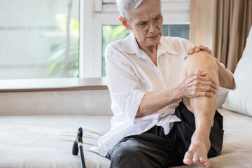 Exhausted asian senior woman hold her knee suffering from pain in knee joint,elderly patient...