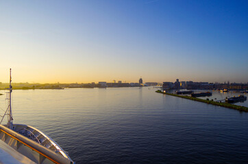Modern cruiseship or cruise ship liner arrival into port of Amsterdam, Holland with city skyline...