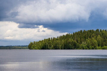Beautiful view of the lake and forest. There are clouds in the sky.