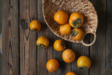 Naklejka na ściany i meble basket with a harvest of persimmons on a wooden table. Country style