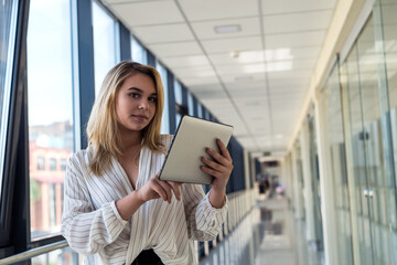 Charm young businesswoman holding digital tablet standing in  corridor of a modern business center