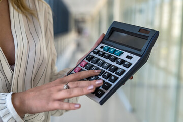 female hand holding calculator in modern business center