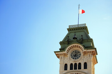 The clock tower and the flag in the bright blue sky