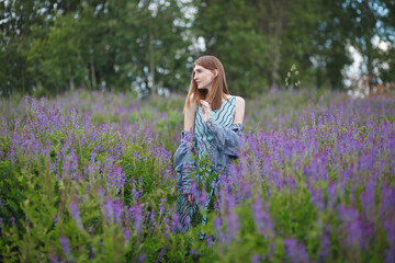 beautiful red-haired girl walking in a field of purple flowers