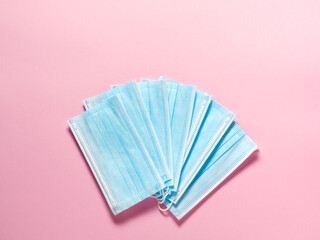Medical protective masks on a pastel pink background. Individual, disposable surgical face mask flat lay pattern. Quarantine healthcare, hygiene and coronavirus protection concept background
