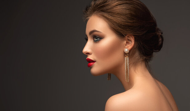 Beautiful woman with red lipstick on her lips and long earrings. Beauty girl with elegant hairstyle and evening make-up. Makeup, cosmetics and jewelry