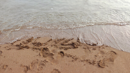 Numbers 2020 year on the sea shore, wave covering lettering. Concept of end awful year