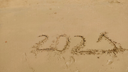 Numbers 2021 year written on the sand in sea beach