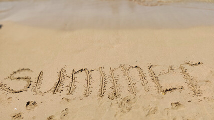 word handwritten summer 2021 on yellow sandy beach