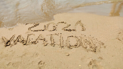 2021 Vacation handwritten inscription in sand of sea beach