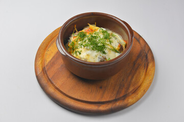 Baked potatoes with mushrooms and cheese in a pot. Delicious dinner. Isolated on white background.