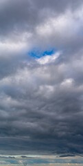 Fantastic clouds against blue sky, vertical panorama
