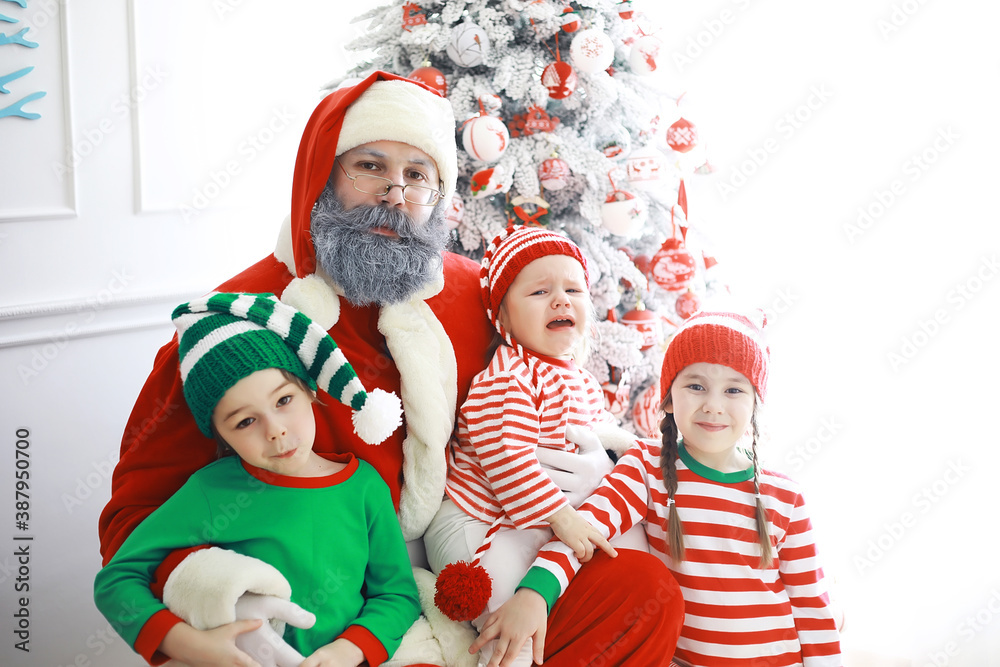 Wall mural santa claus sitting with little cute elves over christmas background. time of miracles. gifts from s