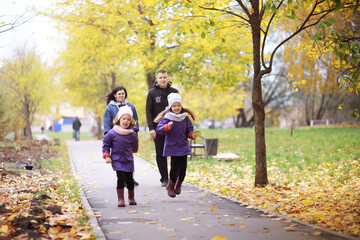 Obraz premium Young family on a walk in the autumn park on a sunny day. Happiness to be together.