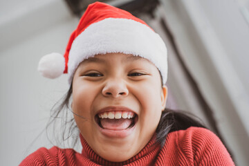 Merry Christmas and Happy Holidays. Happy child with Christmas hat. Joyful baby looking at camera in christmas in the living room at home.