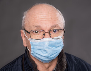 Senior man in protective mask  posing in studio over gray background