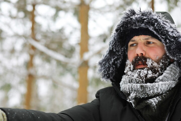 Bearded man in the winter woods. Attractive happy young man with beard walk in the park.