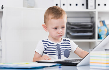 Child is playing on laptop in the office.